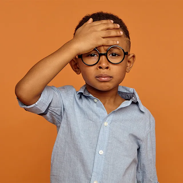 boy with glasses holding head